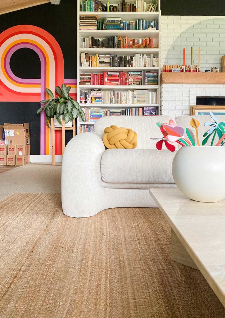 A Hart Jute rug from Revival Rugs in a colorful room with Banyan Bridges mural.