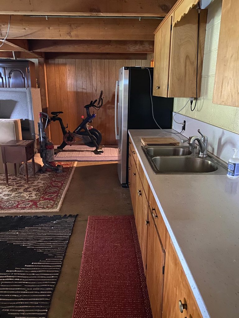 A angled view of the current formica countertops, hideous old fridge, and exercise bike in the corner