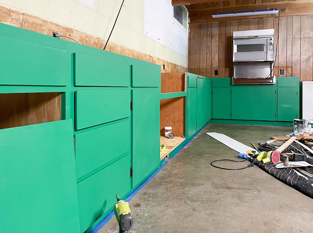 Newly painted green cabinets in an old basement kitchen
