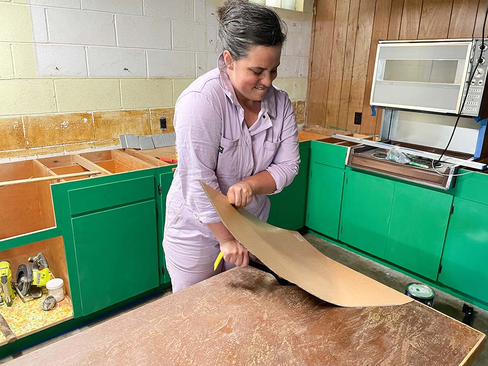 Racheal Jackson of Banyan Bridges removing the formica layer from an antique table