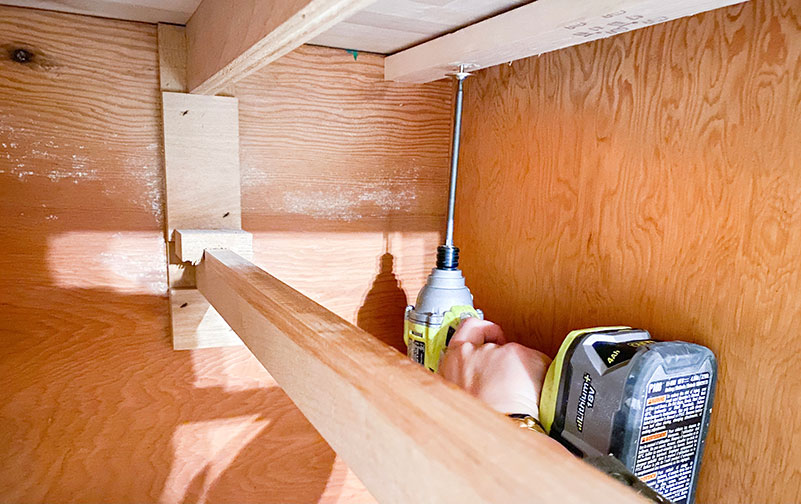 An electric screwdriver inside of cabinetry securing them to the butcher block countertops