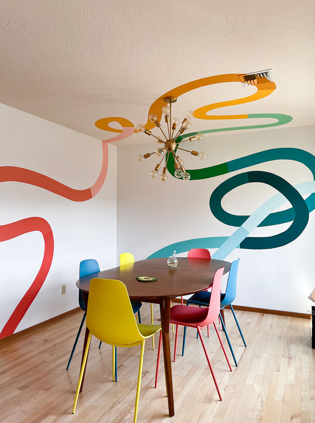 The mural "gummy road" by Racheal Jackson—a colorful, alternating squiggle mural running across the wall and ceiling of a bright kitchen
